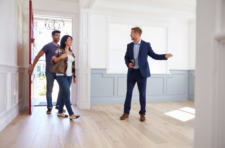 A realtor leading a couple on a tour of the house